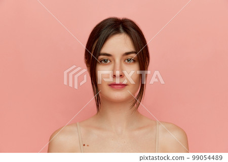 Close-up portrait of beautiful young brunette girl with well-kept skin posing over pink studio background. Concept of body and skincare, beauty 99054489