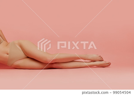 Cropped image of slim smooth female legs over pink studio background. Depilation, epilation, laser hair removal. Concept of body and skincare, beauty Cropped image of slim smooth female legs over pink studio background. Depilation, epilation, laser hair removal. Concept of body and skincare, beauty 99054504