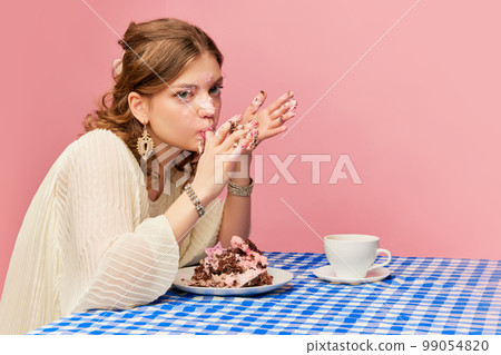 Charming young girl eating cake, pie and drinking tea. Sweet cream mask. Concept of emotions, weird people, retro fashion and humor 99054820