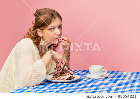 Charming young girl eating cake, pie and drinking tea. Sweet cream mask. Concept of emotions, weird people, retro fashion and humor Charming young girl eating cake, pie and drinking tea. Sweet cream mask. Concept of emotions, weird people, retro fashion and humor 99054821