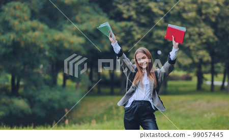 A cheerful student with books in the park in the summer. A cheerful student with books in the park in the summer. 99057445