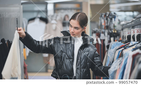A young girl choosing and looking at clothes in the store. A young girl choosing and looking at clothes in the store. 99057470
