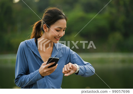 Pleasant sporty woman checking her heart rate data on smartwatch after running in the park. Healthy lifestyle concept Pleasant sporty woman checking her heart rate data on smartwatch after running in the park. Healthy lifestyle concept 99057696