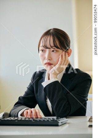 Young woman with a gloomy look at her desk Young woman with a gloomy look at her desk 99058474