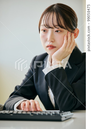 Young woman with a gloomy look at her desk 99058475
