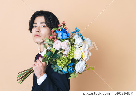 A man in a suit holding a bouquet of flowers 99059497