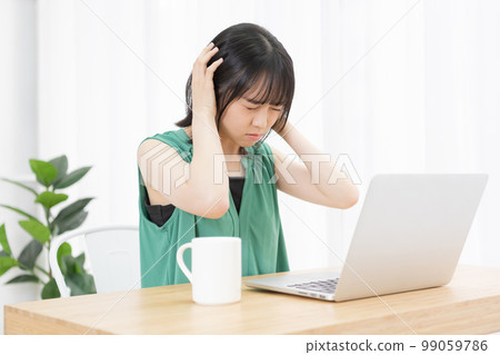 一位因電腦前的噪音而煩惱的年輕女性 99059786
