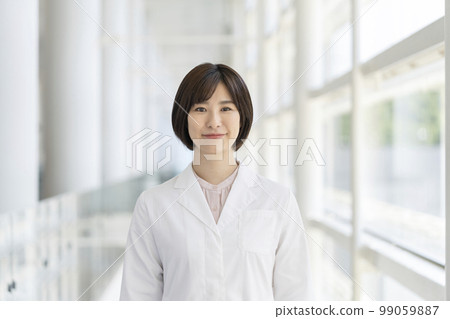 一位身穿白大衣的年輕女子看著相機肖像 99059887