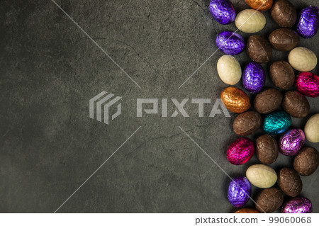 Delicious chocolate easter eggs ,sweets on dark black background,easter concept top view copy space wrapped colorful Delicious chocolate easter eggs ,sweets on dark black background,easter concept top view copy space wrapped colorful 99060068
