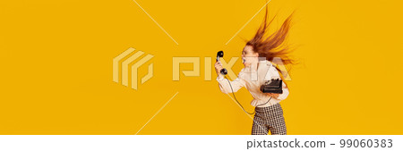 Crazy call. Excited girl with red hair wearing office style clothes shouting at retro vintage phone over yellow background. Concept of youth, student college life, business and education. Crazy call. Excited girl with red hair wearing office style clothes shouting at retro vintage phone over yellow background. Concept of youth, student college life, business and education. 99060383