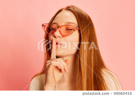 Closeup young beautiful redhaired girl with long hair isolated over light pink background. Concept of positive emotions, happy mood, fashion, youth 99060458