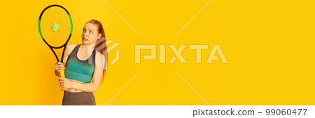 Cute funny young girl in sports fitness clothes holding tennis racket over yellow background. Sport, fitness, happy positive emotions and active lifestyle concept. 99060477