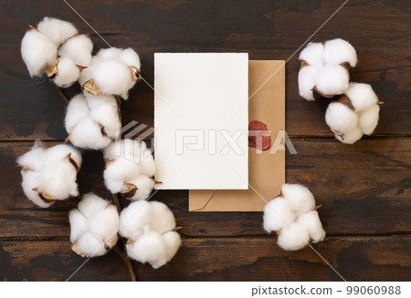 Blank card and envelope with cotton flowers top view on dark brown wood, wedding mockup 99060988
