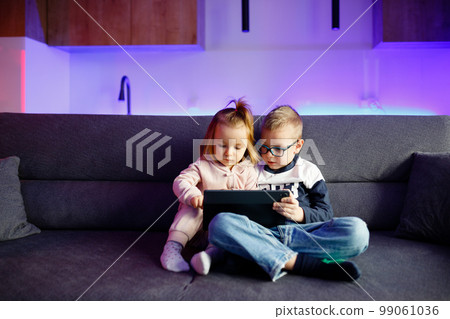 Danya's older brother teaches her younger sister how to use a tablet. 99061036