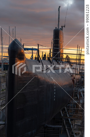 Submarine under repair in port against the backdrop of an orange sunset Submarine under repair in port against the backdrop of an orange sunset 99061228