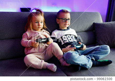 The boy Danya and his younger sister Emilia play on the console. 99061500