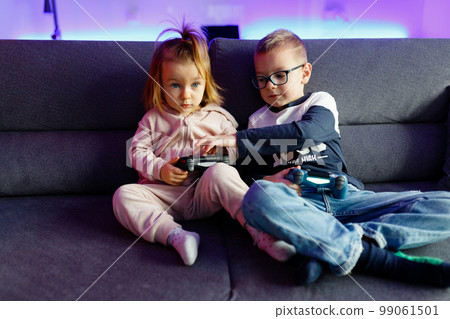 The boy Danya and his younger sister Emilia play on the console. 99061501