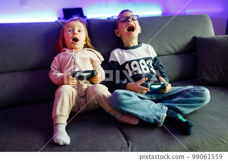 The boy Danya and his younger sister Emilia play on the console. 99061559