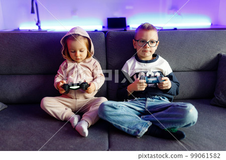 The boy Danya and his younger sister Emilia play on the console. 99061582