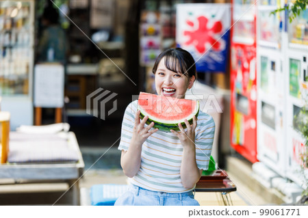Young woman eating watermelon at tourist shop 99061771