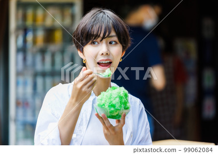 Young woman eating shaved ice at a tourist spot Young woman eating shaved ice at a tourist spot 99062084