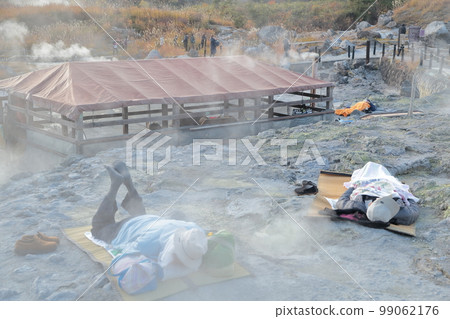A hot spring cure visitor enjoying a bedrock bath on a natural rocky stretch (Tamagawa Onsen, Semboku City, Akita Prefecture) 99062176