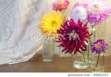 Dahlias in glasses on a wooden table. View through wet rainy windowPInk white Dahlia flowers, top view. Colorful dahlia flowers mix wallpaper background. 99062457