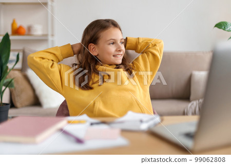 Portrait of happy girl sitting at a table with a laptop Portrait of happy girl sitting at a table with a laptop 99062808