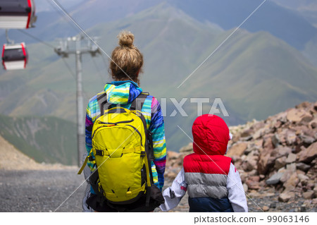 Mom with a child, the family travels through the mountains, rides the funicular. 99063146