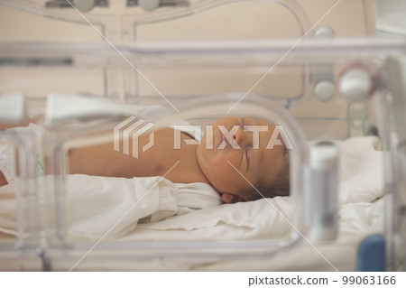 Neonatology. A newborn in a special incubator for babies in a hospital. Neonatology. A newborn in a special incubator for babies in a hospital. 99063166
