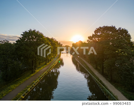 Beautiful sunset over a river with green bushes and color rich sky Beautiful sunset over a river with green bushes and color rich sky 99063483