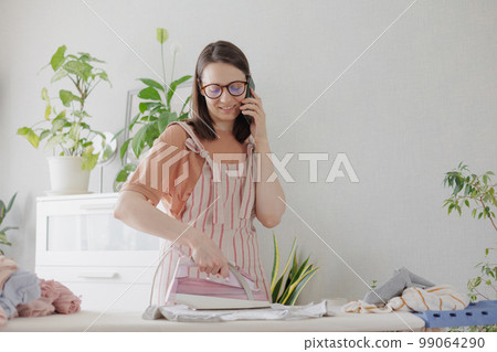 woman irons linen and clothes home, laundry housework textile care. female housewife  99064290
