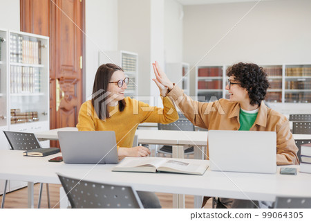 Two female students give high fives and rejoice at victory in creative project Two female students give high fives and rejoice at victory in creative project 99064305