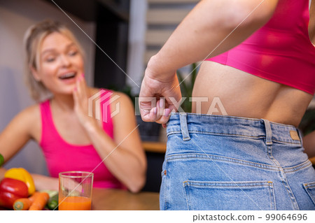 woman standing backwards pulls at the waist for loose pants 99064696