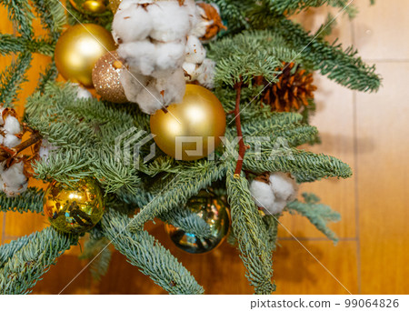 Decorated Christmas Tree, Golden Christmas Decorations, Shiny Garland on Green Branches, Blurred Background 99064826