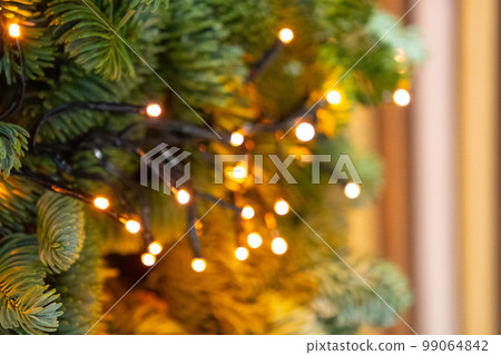 Decorated Christmas Tree, Christmas Decorations, Shiny Garland on Green Branches, Blurred Background Decorated Christmas Tree, Christmas Decorations, Shiny Garland on Green Branches, Blurred Background 99064842