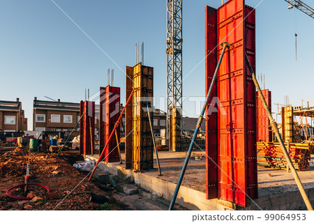 Construction site with steel formworks and reinforcing bars for pillars ready for concrete 99064953