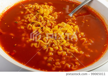 Red Spicy Noodle Soup in White Bowl, Hot Chili Pepper Ramen Closeup Red Spicy Noodle Soup in White Bowl, Hot Chili Pepper Ramen Closeup 99065011