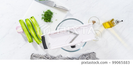 Flat lay. Slicing vegetables on slicer to make summer cucumber salad. Flat lay. Slicing vegetables on slicer to make summer cucumber salad. 99065883