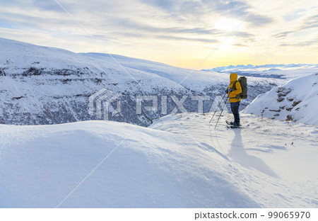 Snow shoe hiking on a beautiful sunny day at a mountain peak of Dovrefjell Snow shoe hiking on a beautiful sunny day at a mountain peak of Dovrefjell 99065970