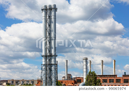 The tall white chimneys of the thermal station rise above the city. The tall white chimneys of the thermal station rise above the city. 99065974