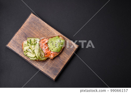 Delicious brown bread toast with salmon, avocado, cucumber and sesame seeds Delicious brown bread toast with salmon, avocado, cucumber and sesame seeds 99066157
