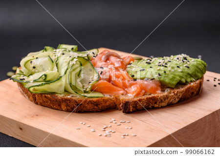 Delicious brown bread toast with salmon, avocado, cucumber and sesame seeds Delicious brown bread toast with salmon, avocado, cucumber and sesame seeds 99066162