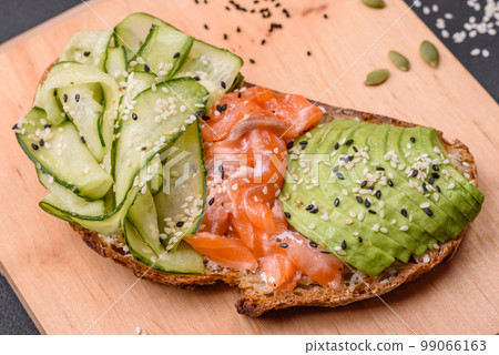 Delicious brown bread toast with salmon, avocado, cucumber and sesame seeds Delicious brown bread toast with salmon, avocado, cucumber and sesame seeds 99066163
