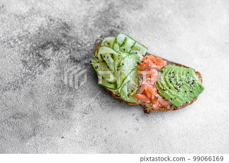 Delicious brown bread toast with salmon, avocado, cucumber and sesame seeds Delicious brown bread toast with salmon, avocado, cucumber and sesame seeds 99066169
