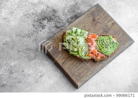 Delicious brown bread toast with salmon, avocado, cucumber and sesame seeds 99066171