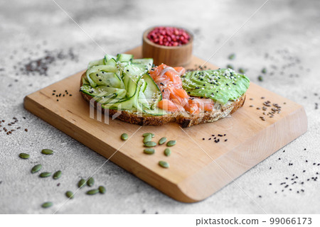 Delicious brown bread toast with salmon, avocado, cucumber and sesame seeds 99066173