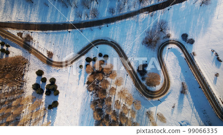 A winding bike path in a city park. City park in winter. Snow lies on the ground. Aerial photography. 99066335