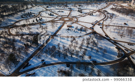 A winding bike path in a city park. City park in winter. Snow lies on the ground. Aerial photography. A winding bike path in a city park. City park in winter. Snow lies on the ground. Aerial photography. 99066338