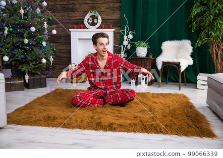 A man sits on a fluffy carpet with his legs crossed. 99066339